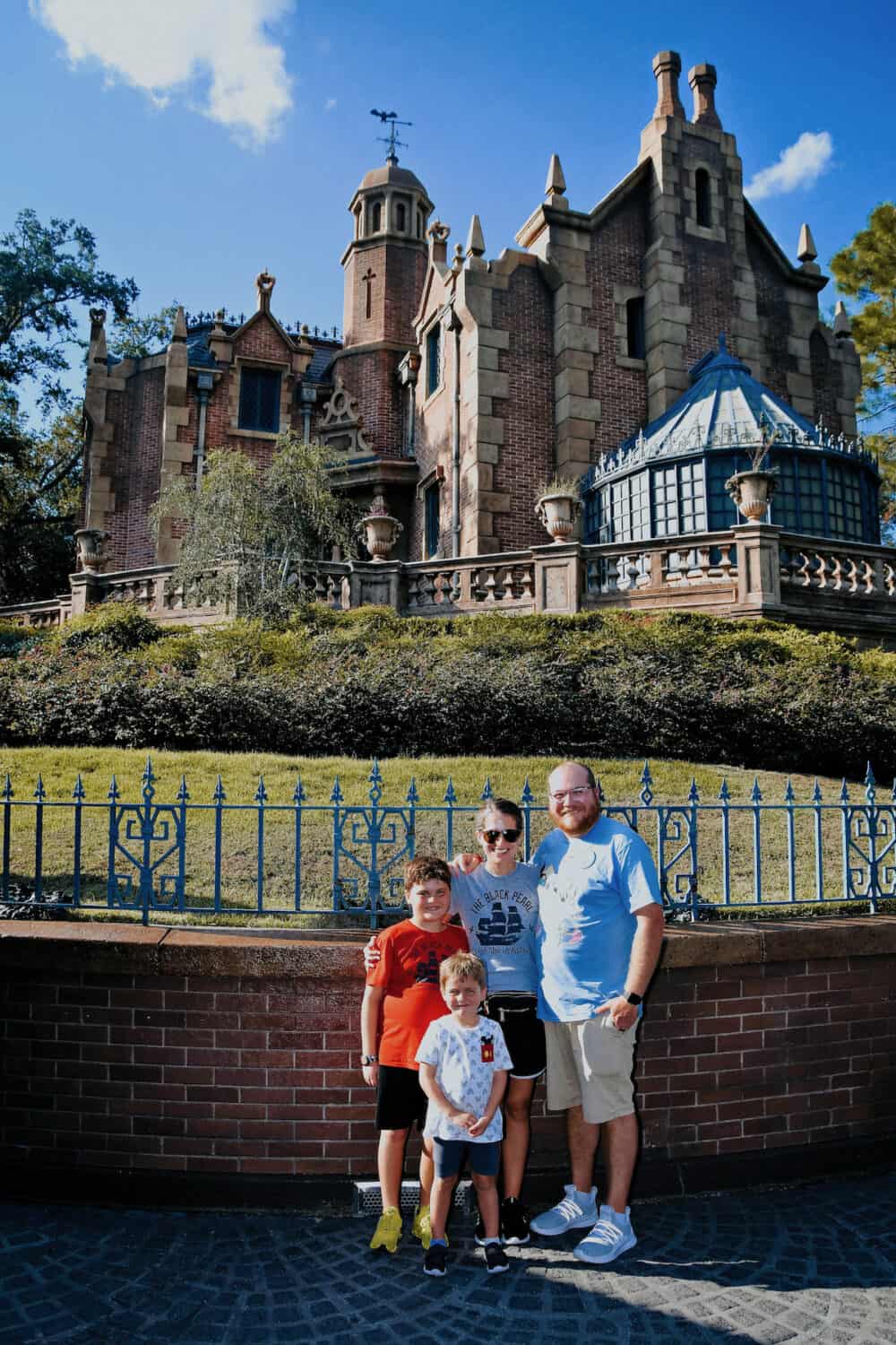 family of four posing in front of Haunted Mansion in Disney World 