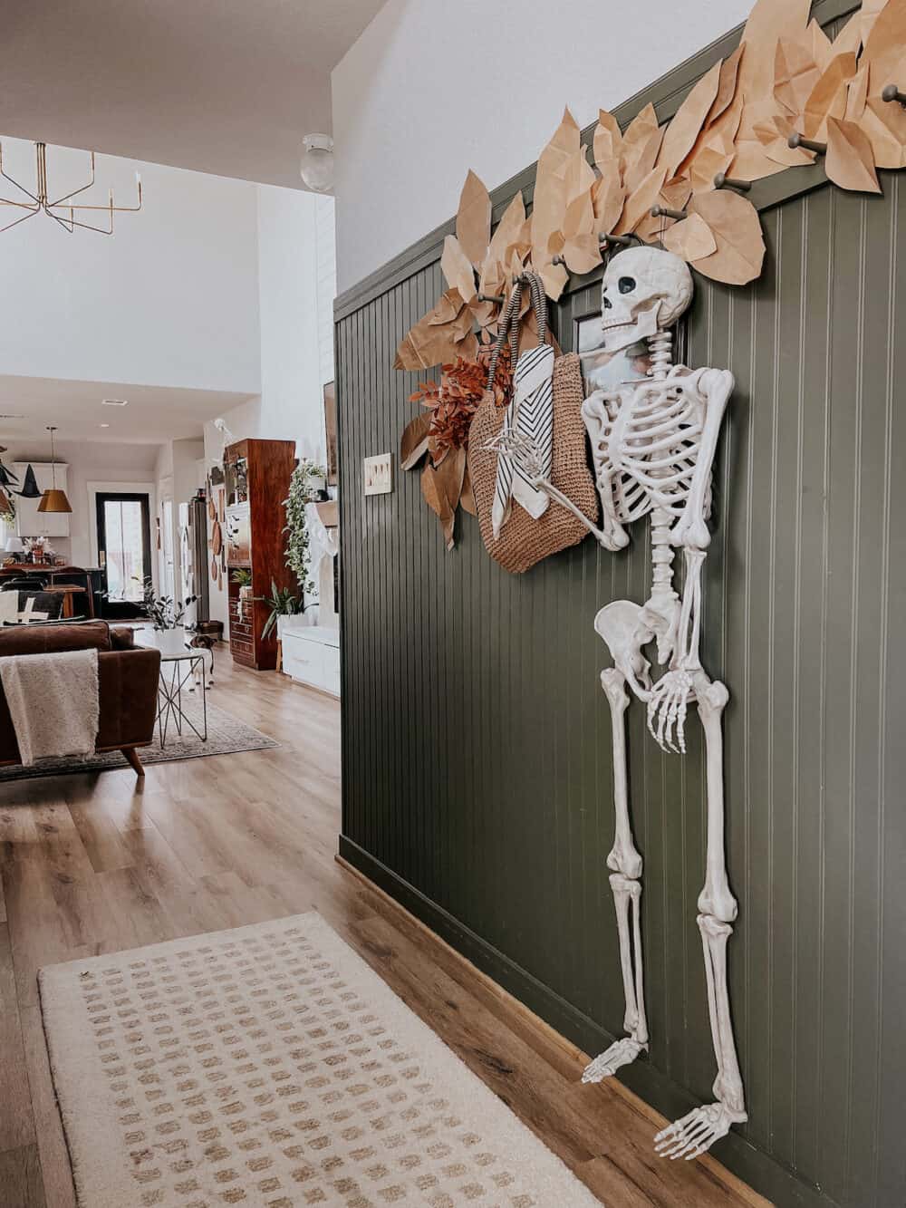 entryway with bead board paneling and a large skeleton hanging from peg hooks 