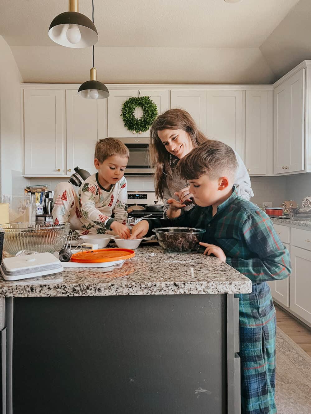 mom and two boys baking cookies together 