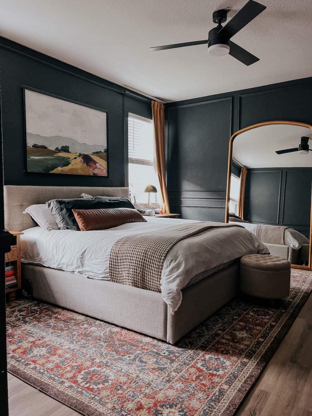 a primary bedroom with dark blue walls and picture frame molding 