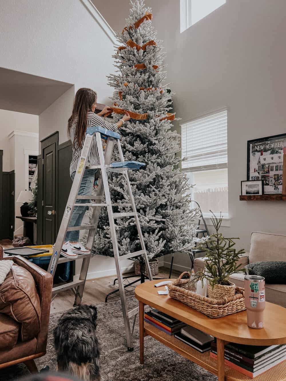 Woman adding gold ribbon to a Christmas tree 