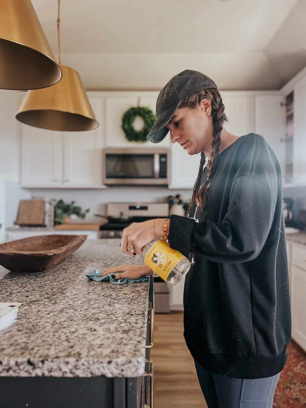 Woman cleaning a counter using Caldrea countertop cleaner and a microfiber cloth 