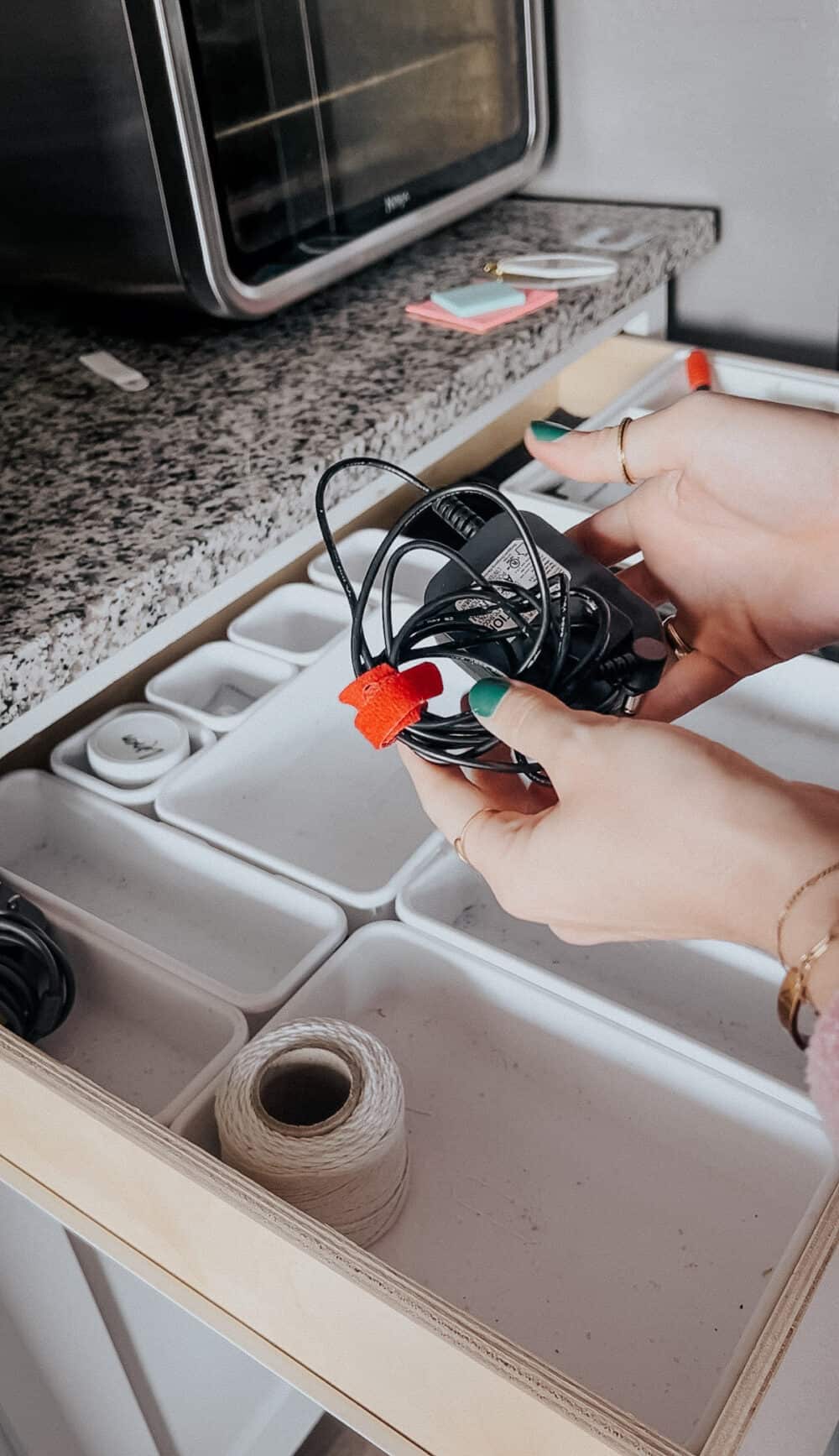 Woman's hand holding a cord organized with a velcro cord organizer 