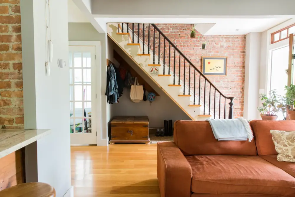 a living room with a view of a staircase that has a brick accent wall 