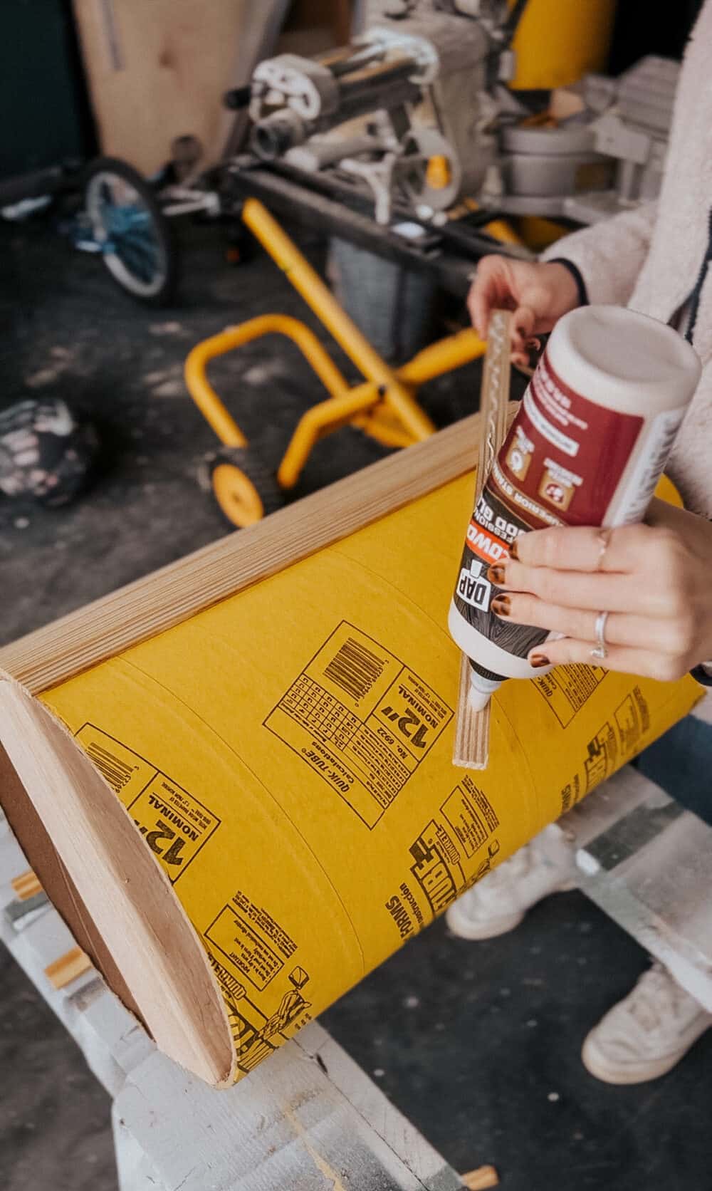 woman using wood glue to attach trim to a concrete form 