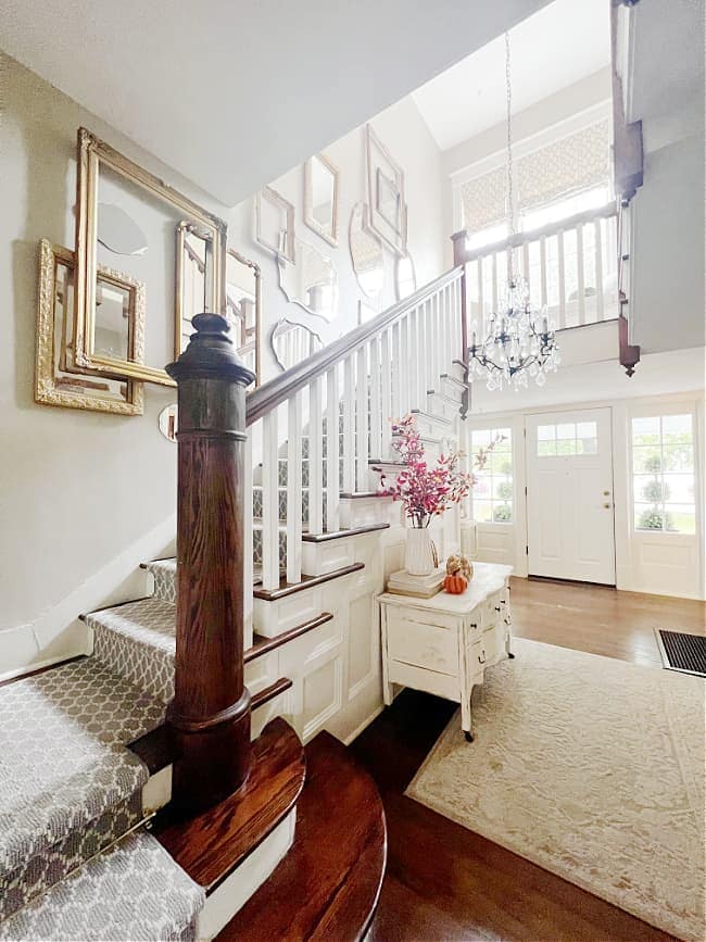 a staircase with a collection of mirrors hanging on the wall 