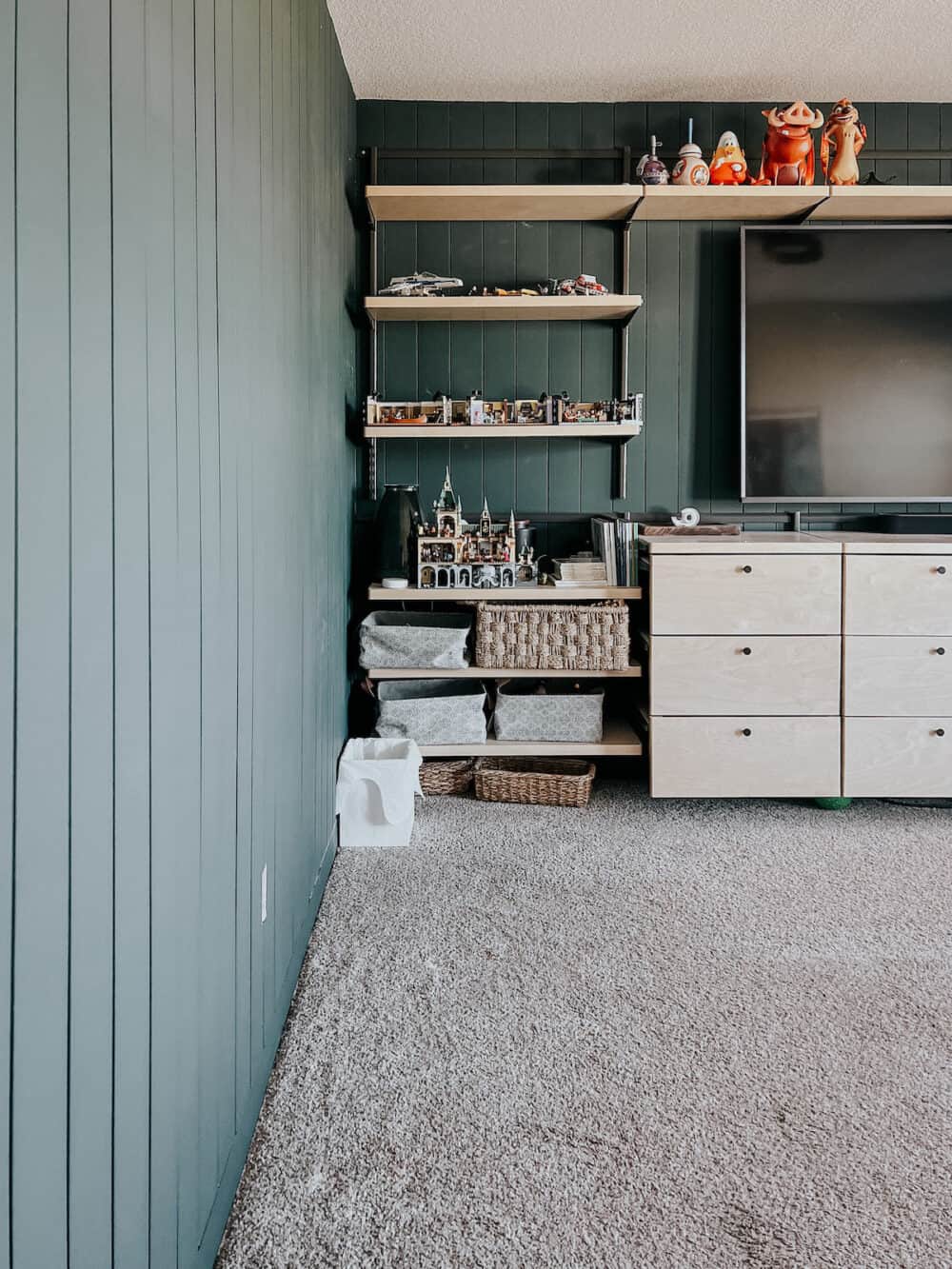 Family room with built in shelving and dark green vertical shiplap 