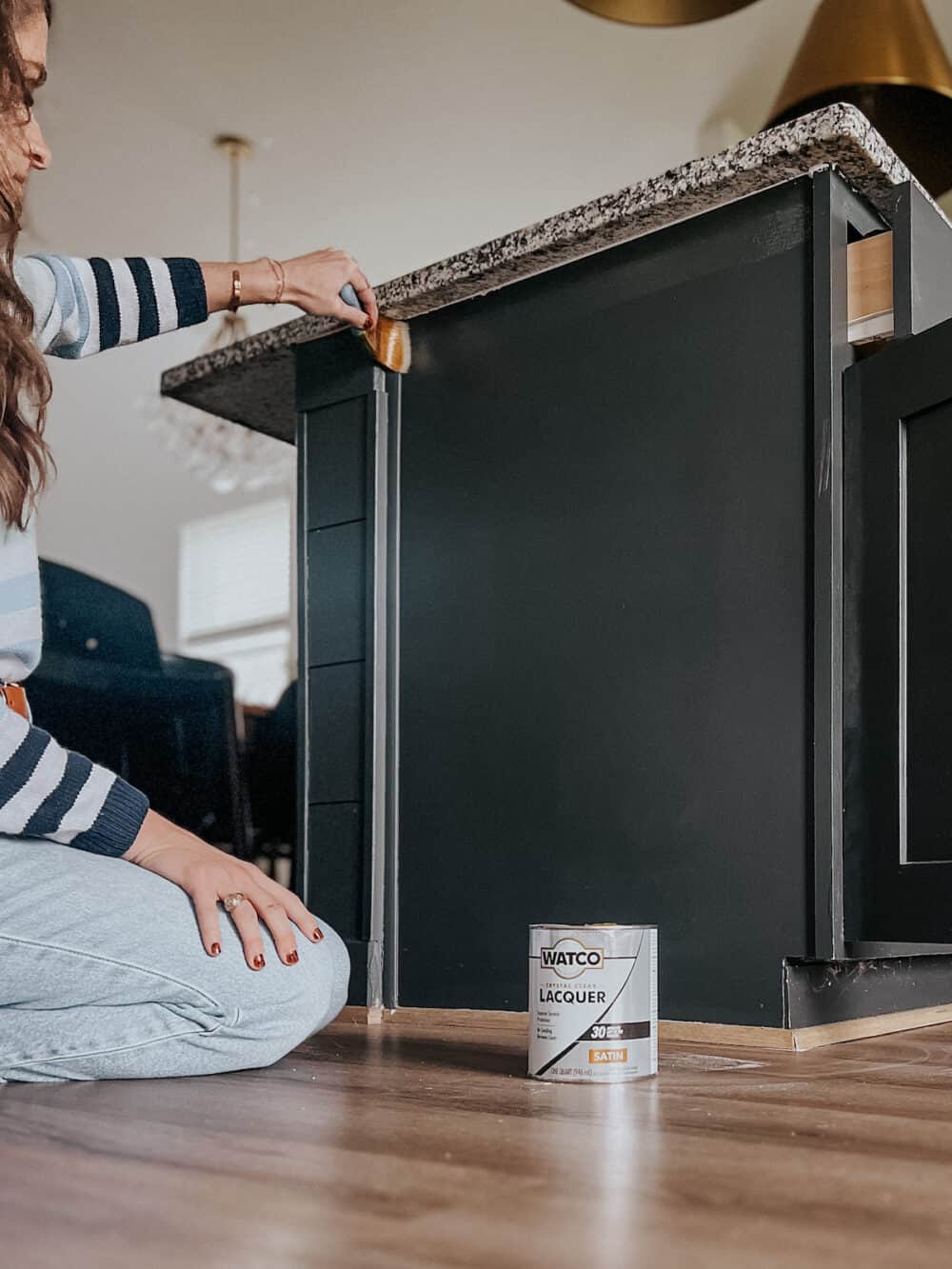 woman using Watco Laquer to seal painted kitchen cabinets 