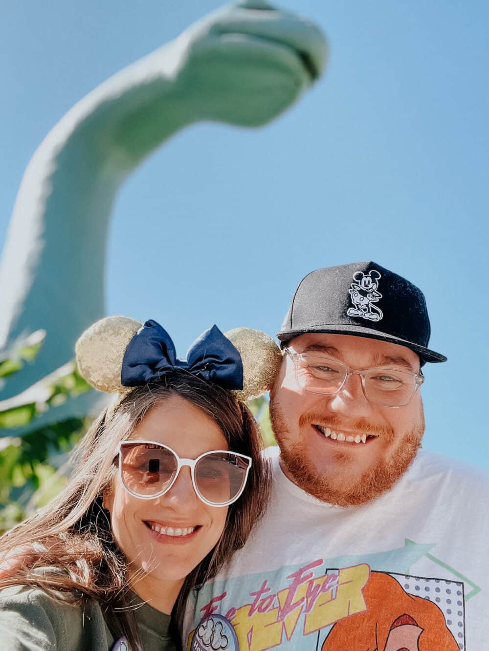 couple smiling in front of Gertie the dinosaur at Hollywood Studios in Disney World 