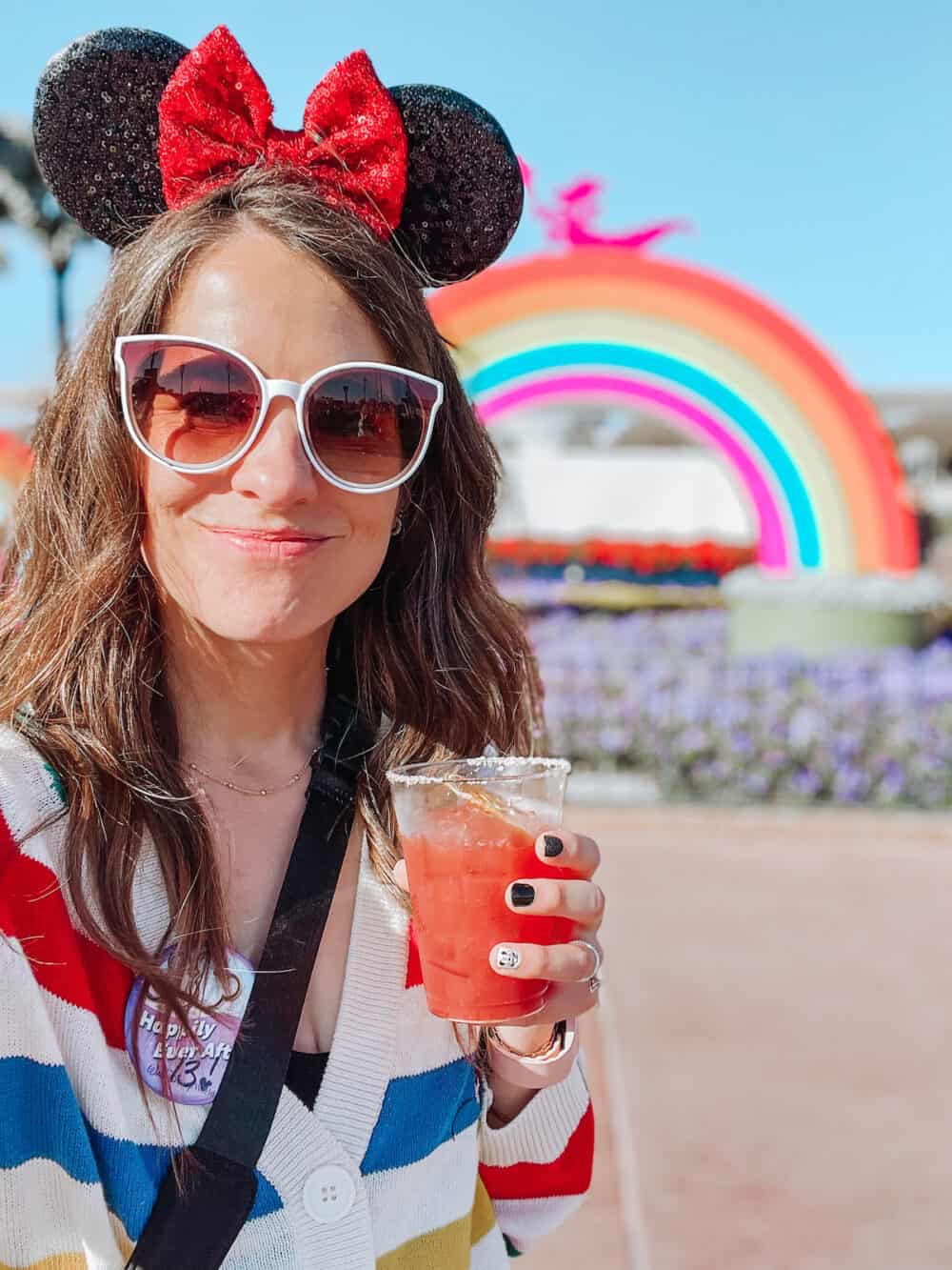 woman holding a drink and smiling at Epcot's Festival of the Arts 