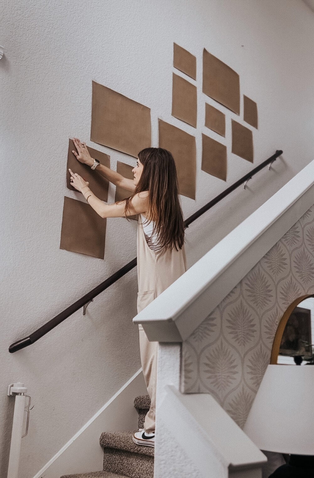 woman hanging a gallery wall paper template on the wall
