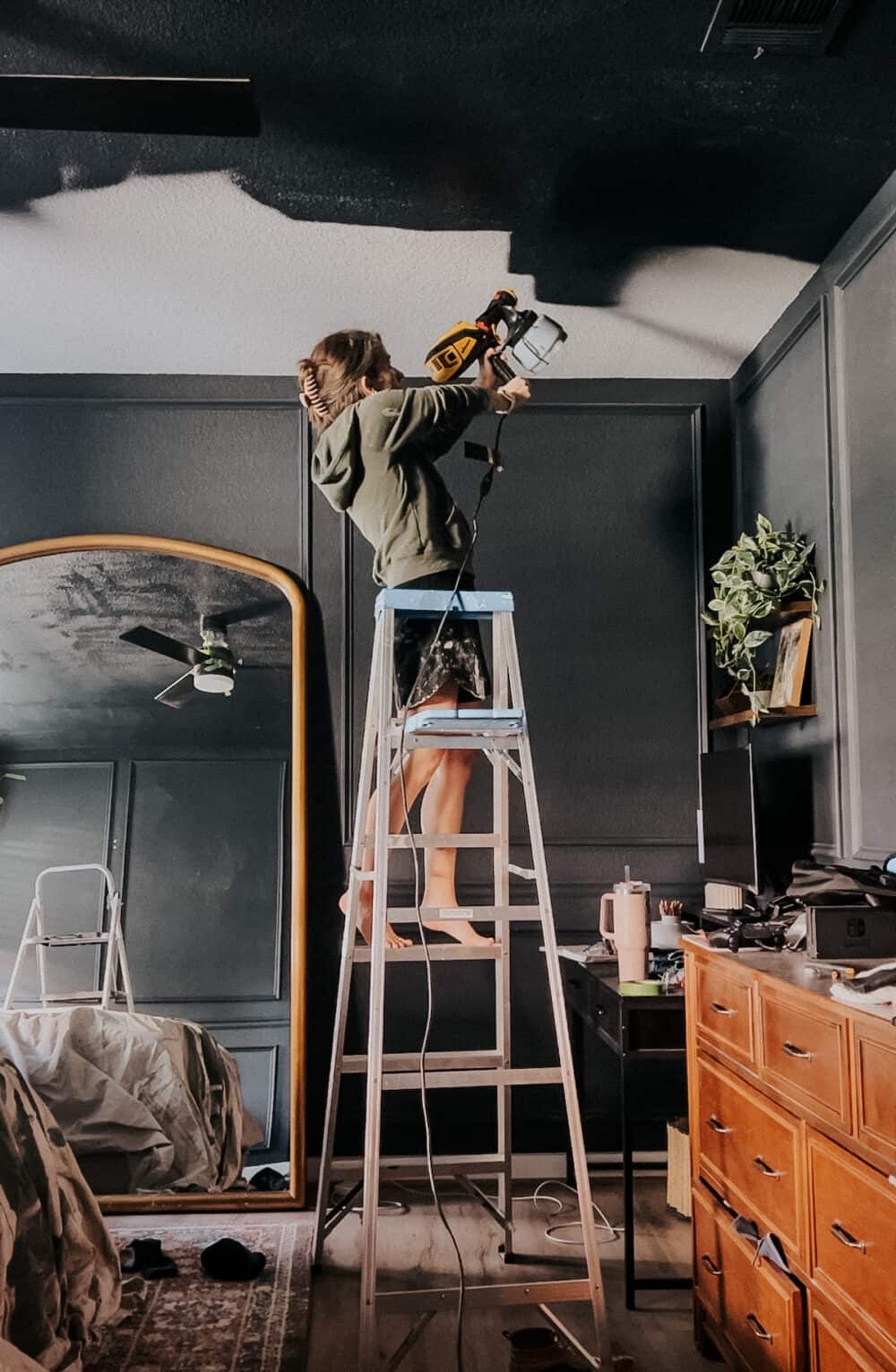 woman painting a ceiling with a paint sprayer 
