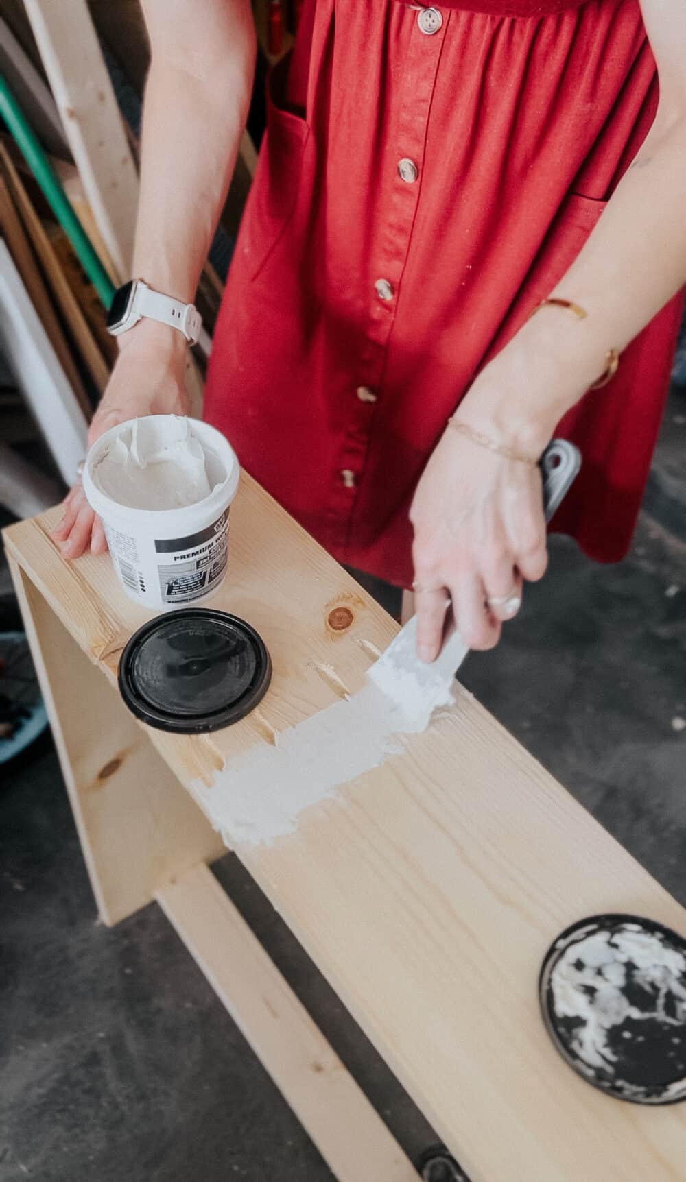 woman applying dap professional wood glue to a DIY sofa table