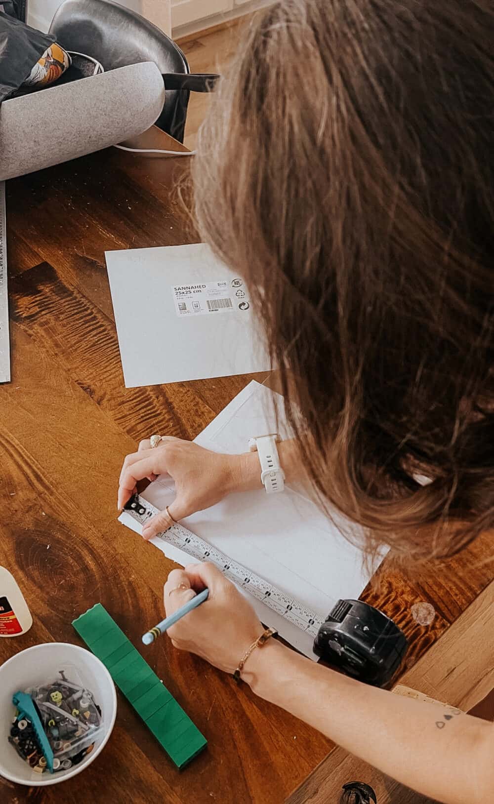 woman tracing lines onto a picture mat to create a lego minifig display