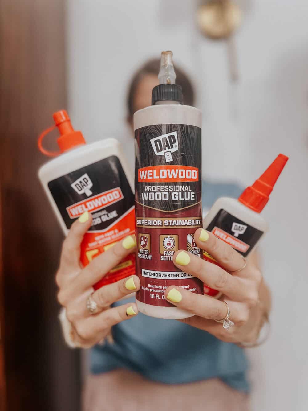 woman holding three different DAP brand wood glue products