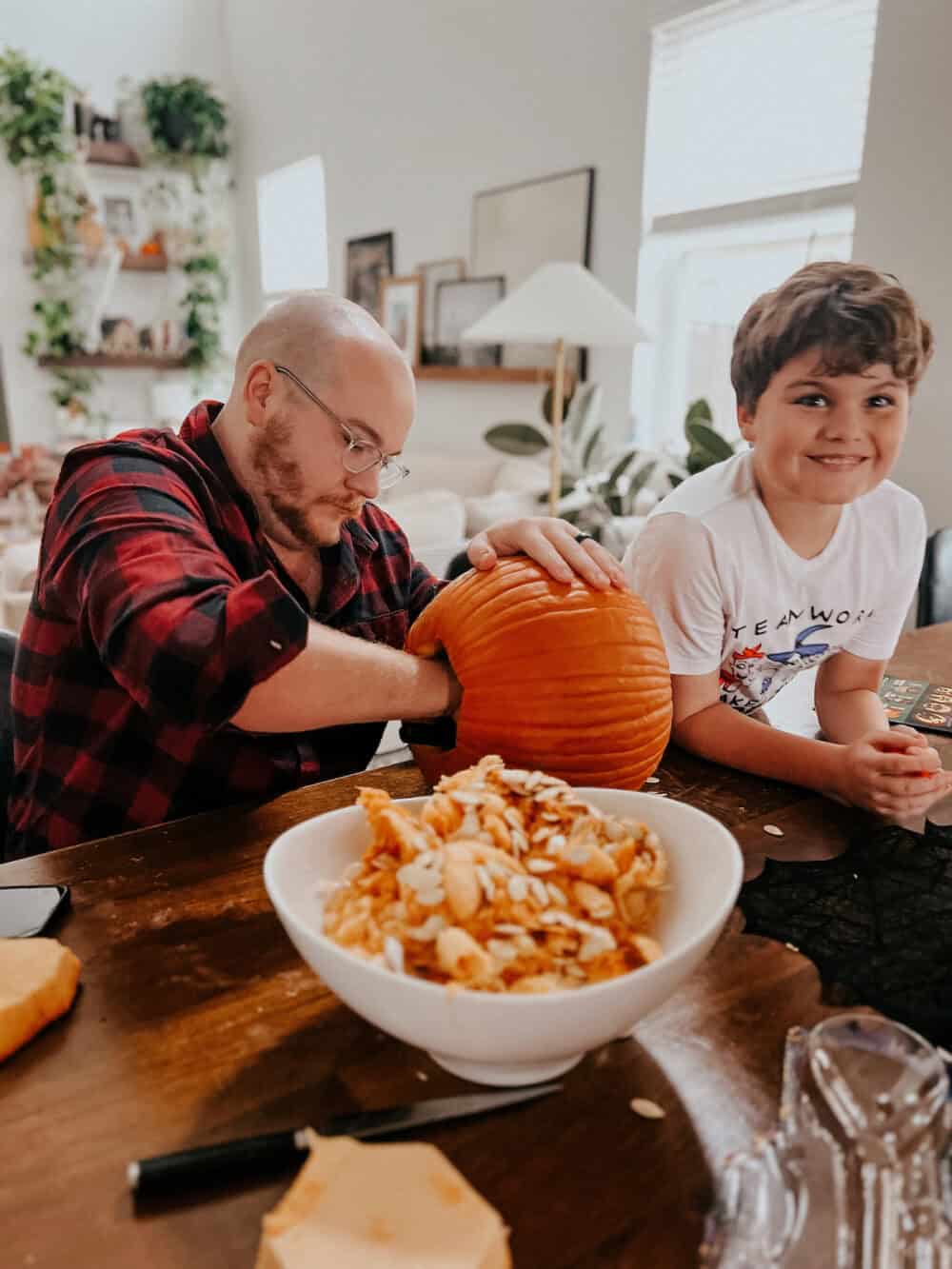 boy and his dad carving halloween pumpkin