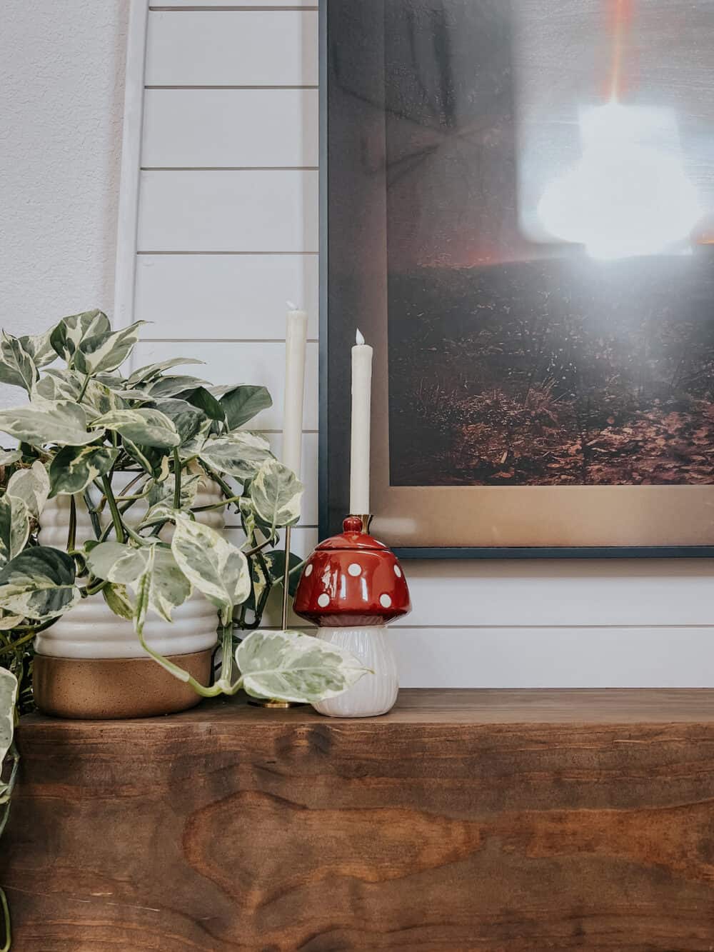 a fireplace mantel with a small mushroom decor piece and two candles
