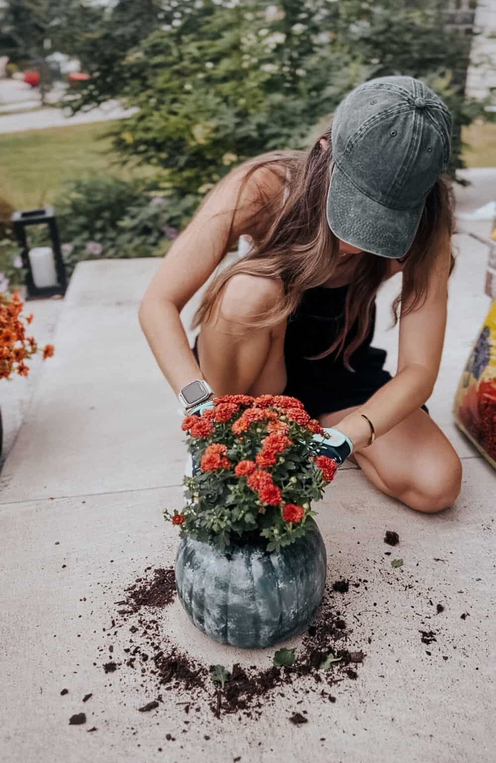 mujer plantando una mamá en una calabaza falsa