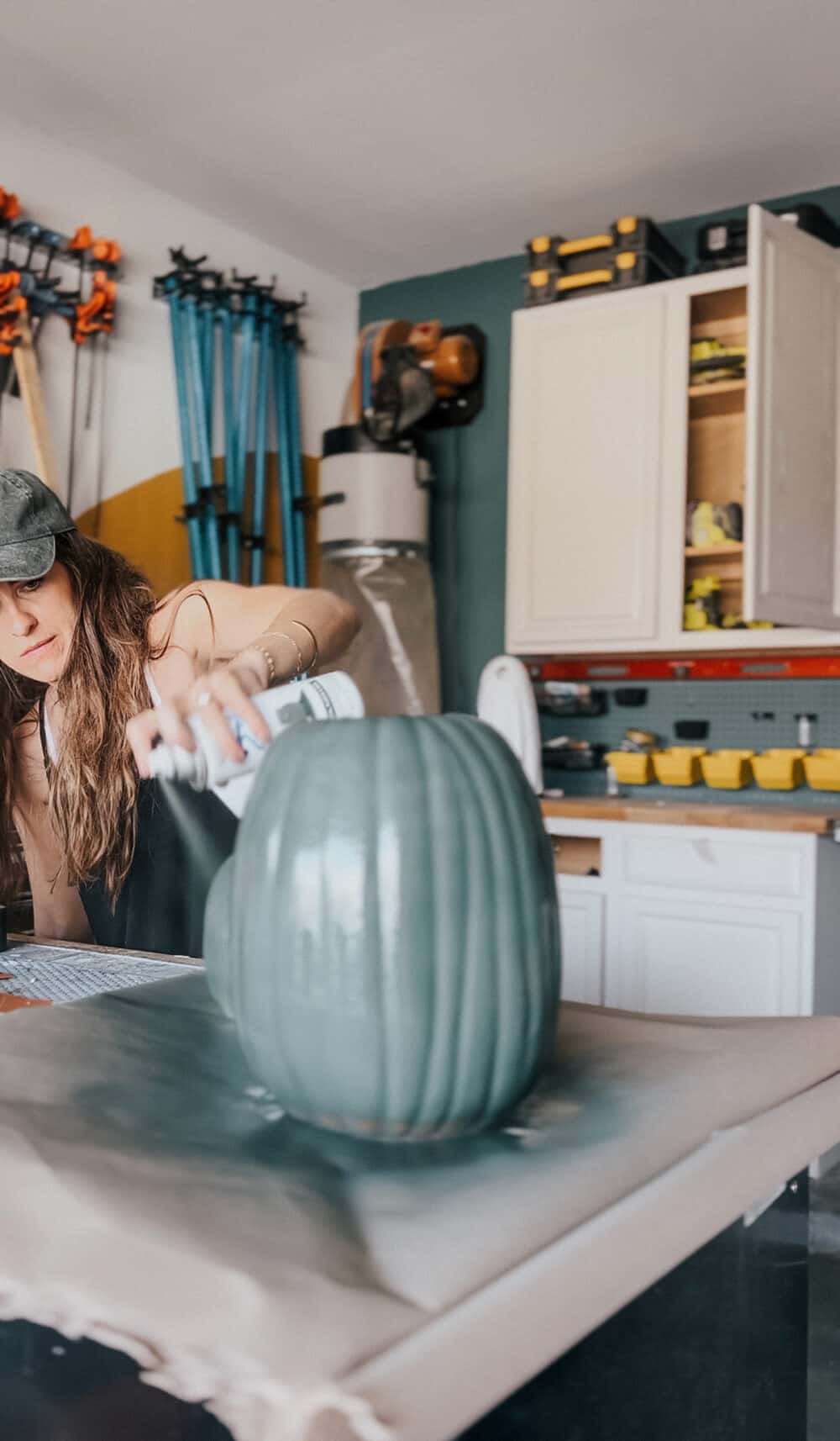 mujer pintando una calabaza falsa con pintura en aerosol