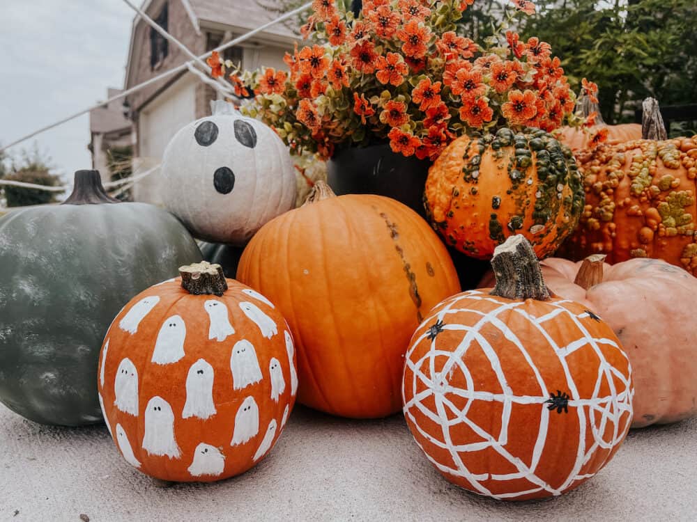 collection of painted pumpkins along with regular pumpkins on a front porch