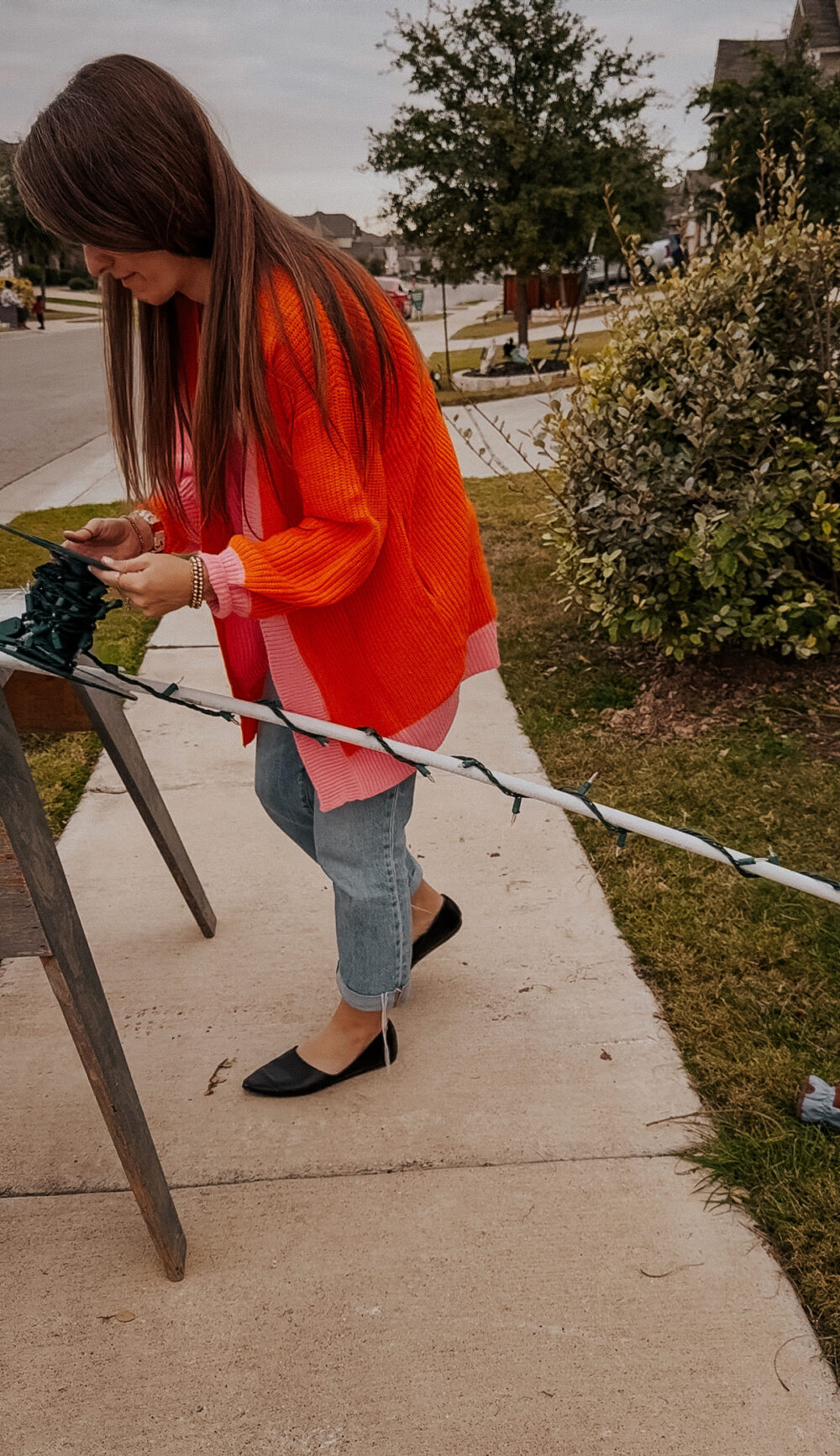 woman wrapping lights around PVC pipe to create Christmas arches 