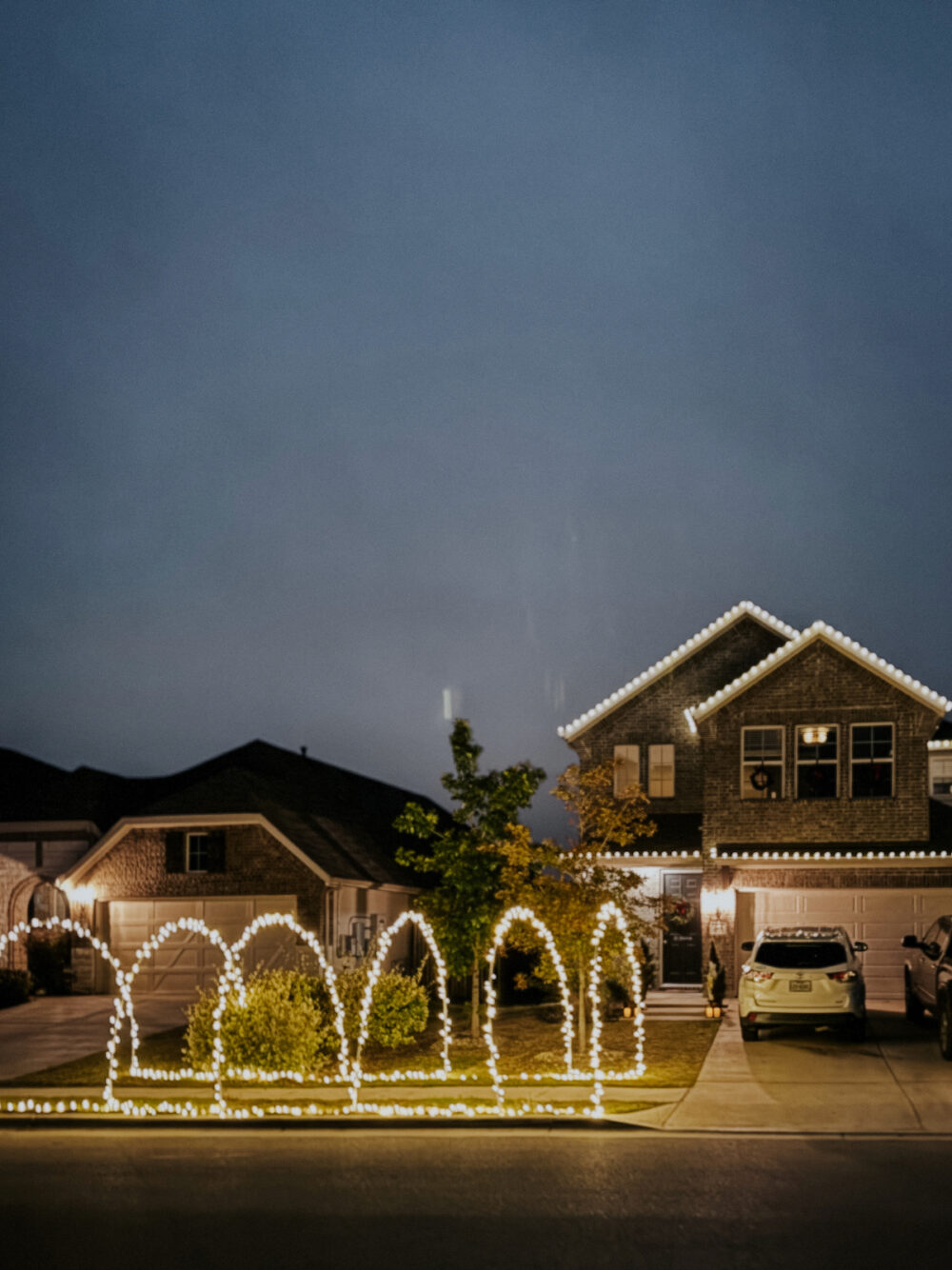 House with lighted Christmas arches on sidewalk
