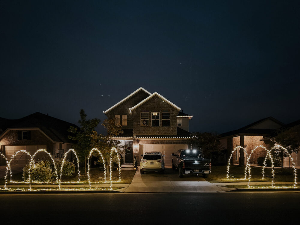 house with lighted Christmas arches on the sidewalk