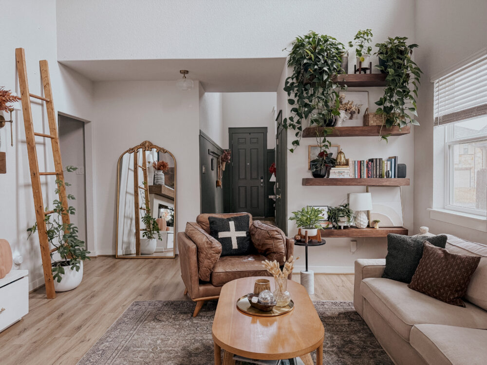 a cozy and neutral living room with green and. brown decor and lots of plants