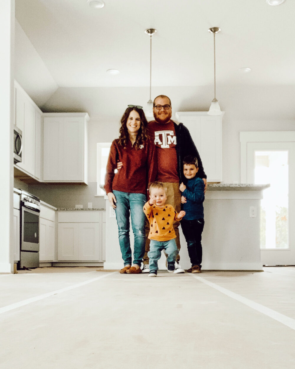 family standing in a kitchen in an in-progress house 