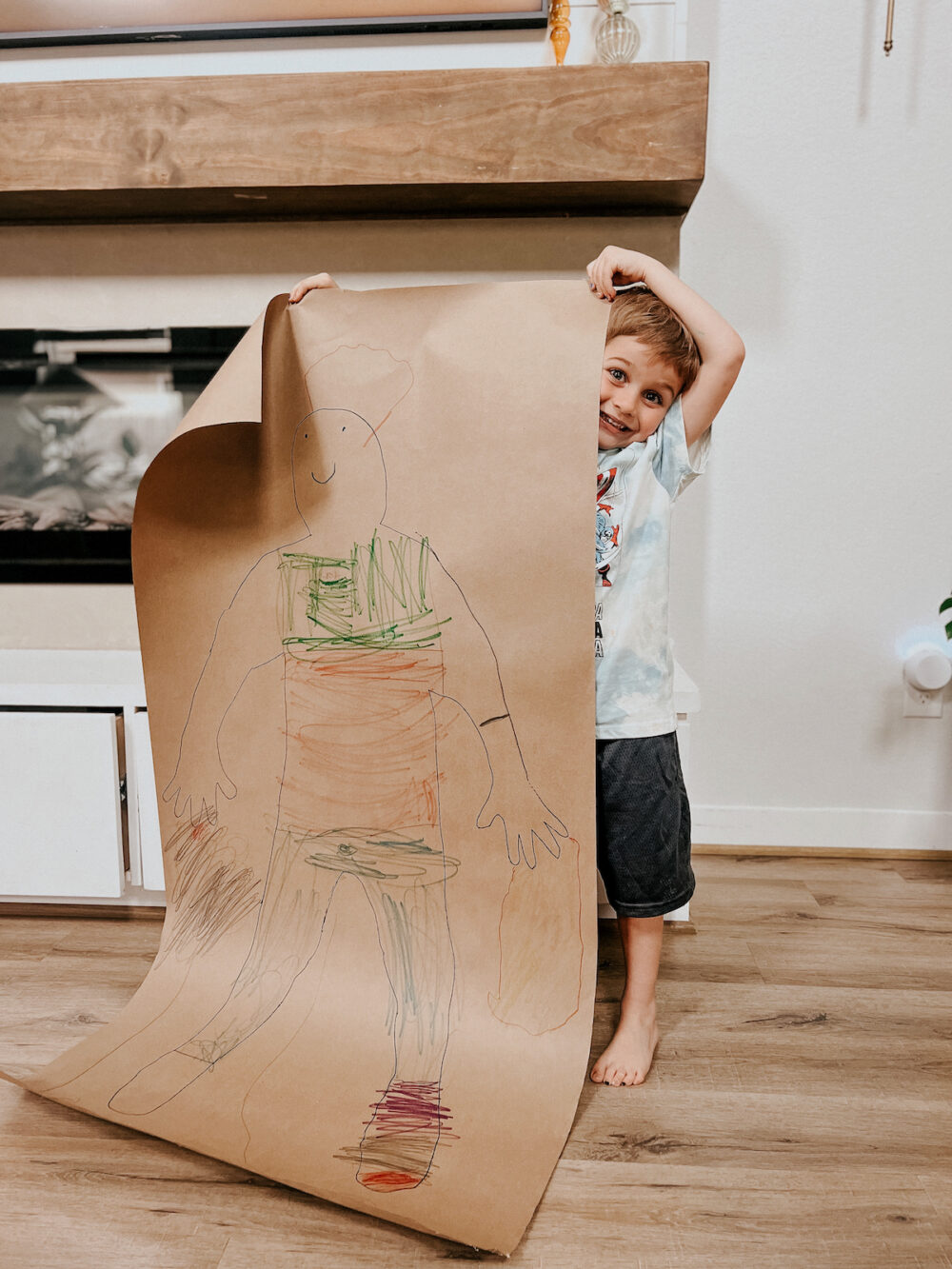 young boy holding up a life-size self portrait