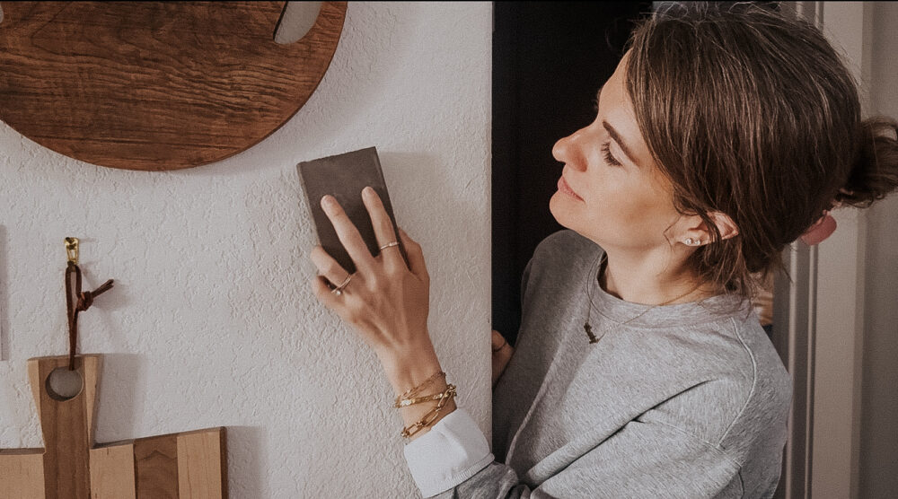 woman sanding a patch on a wall