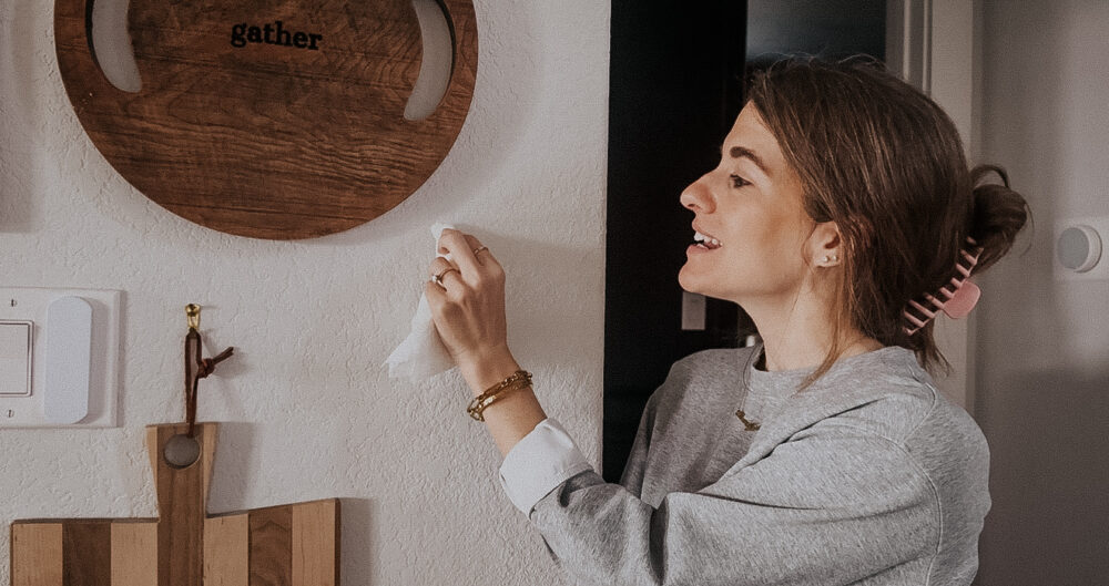 woman using a paper towel to touch up paint on drywall