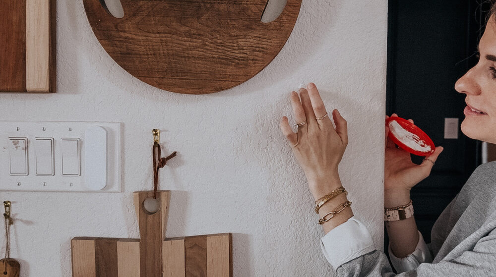 woman's hand applying spackling to a nail hole in the wall