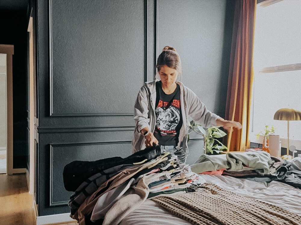 woman going through a pile of clothes on a bed