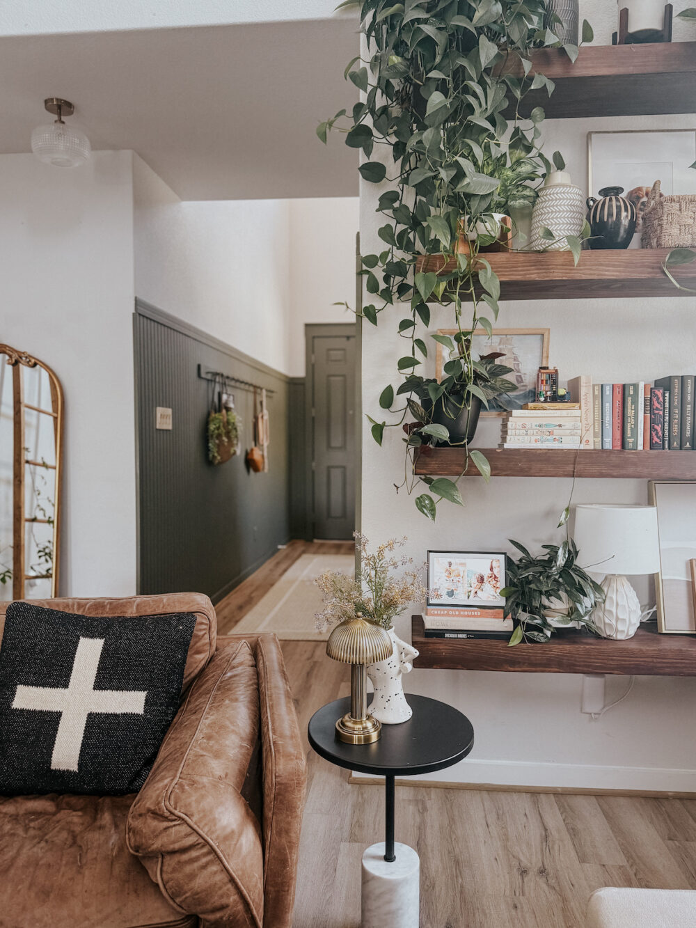 corner of a living room with a pretty shelf and lots of plants 