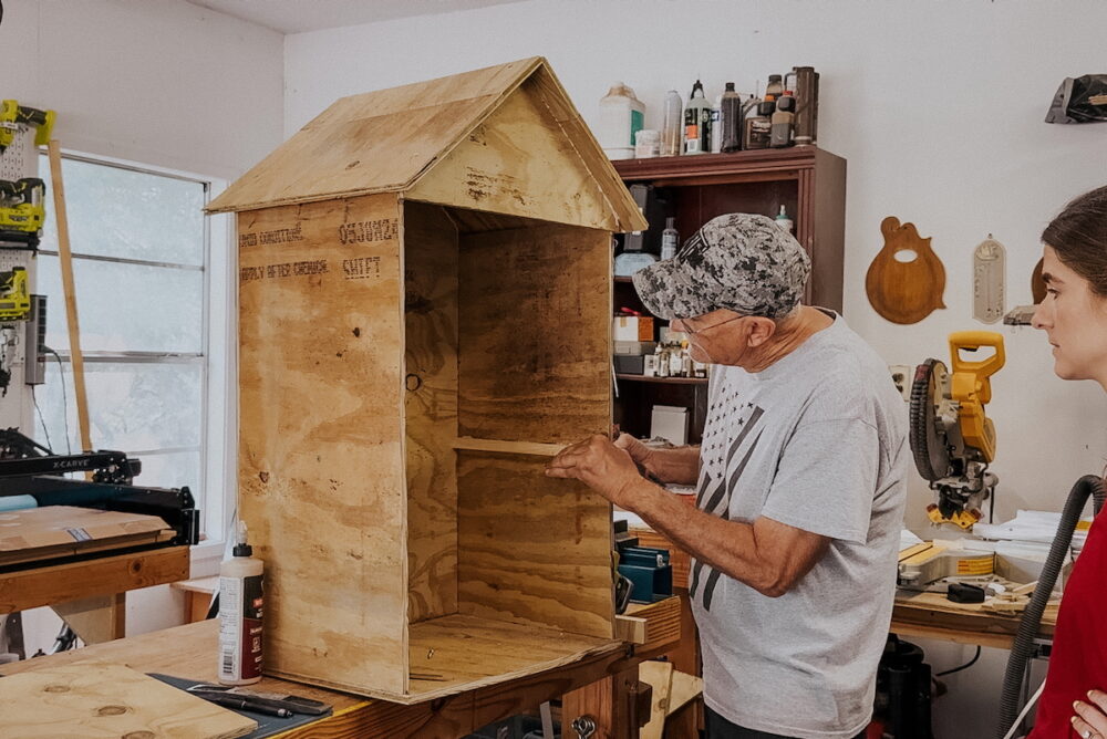 Man adding support piece for shelf in a puzzle Little Free Library