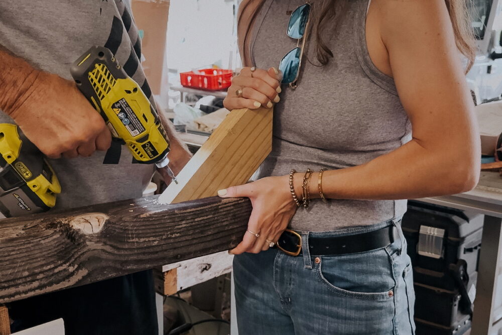 Woman and man attaching supports to a post for a Free Little Library