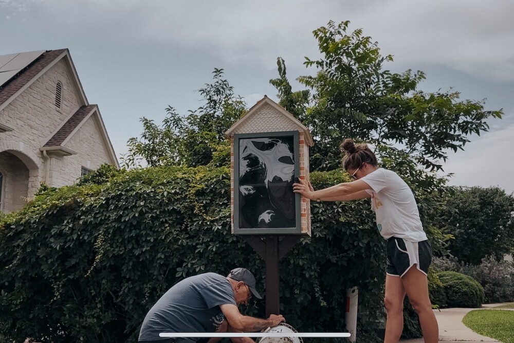 Woman and man installing a post in the ground with concrete