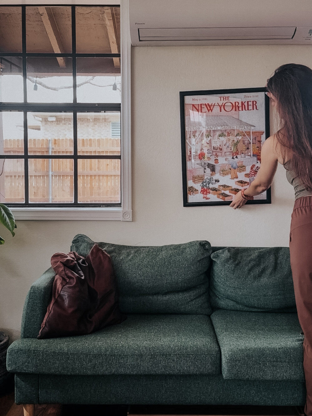 woman hanging a framed puzzle on a wall