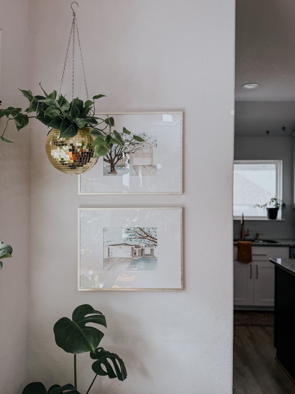 corner of a dining room with paintings of homes on the wall