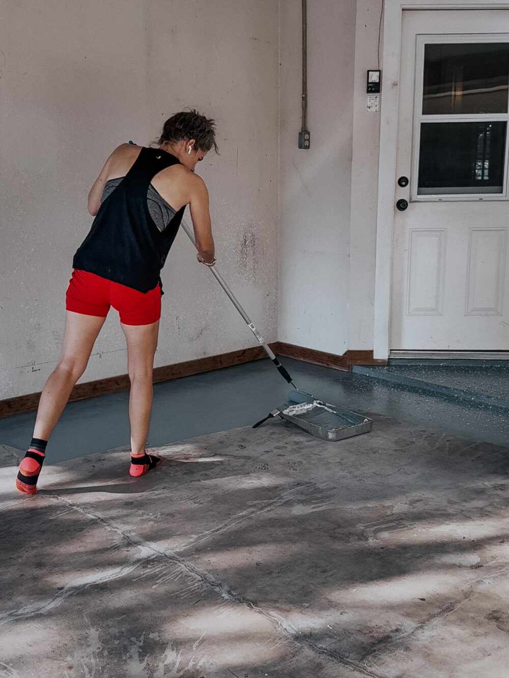 woman painting a garage floor with an epoxy floor kit 