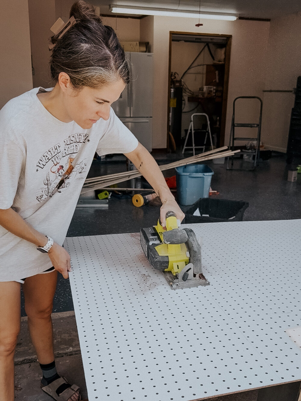 woman cutting a pegboard using a circular saw
