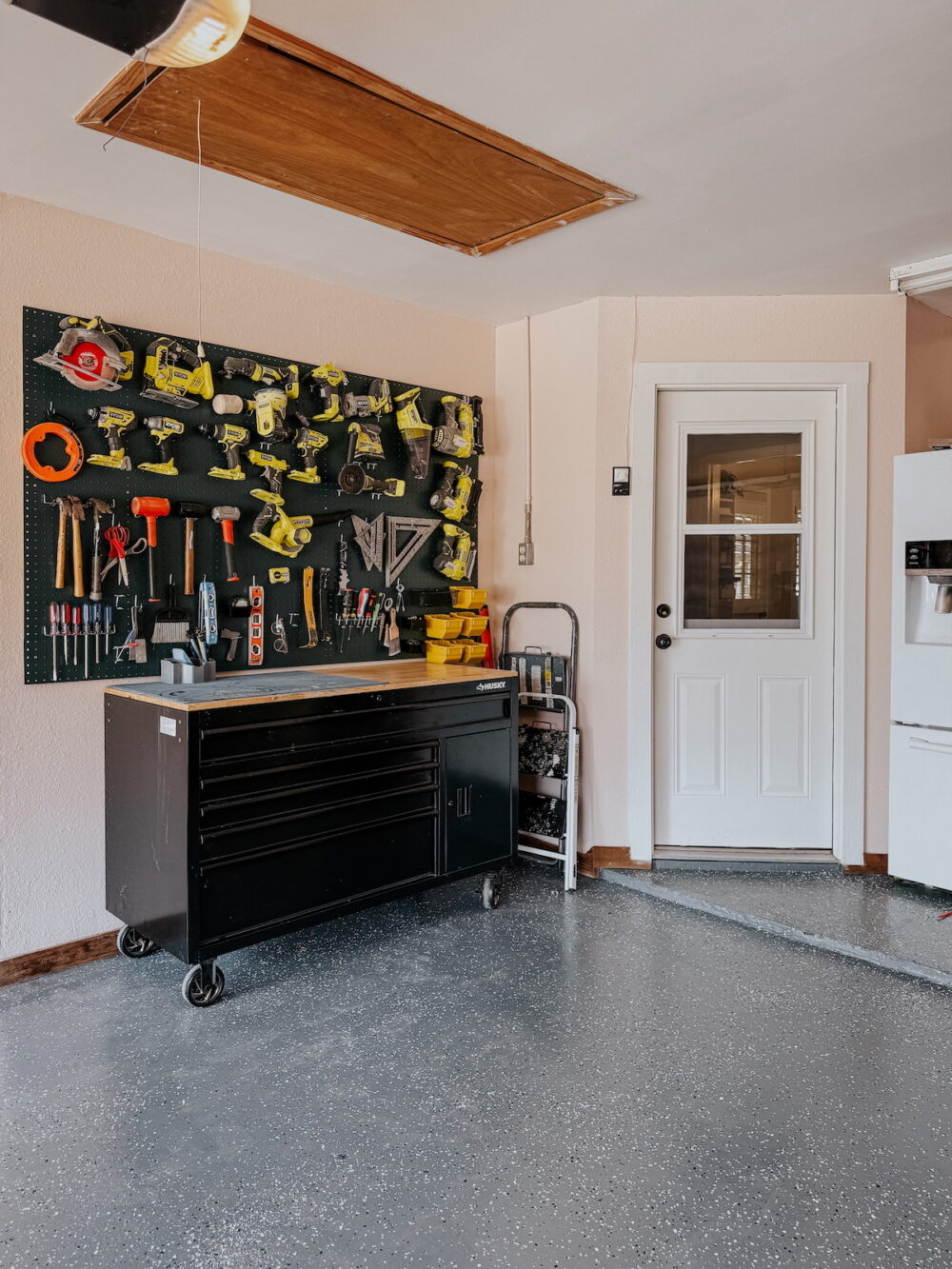 garage with a work bench and a large pegboard