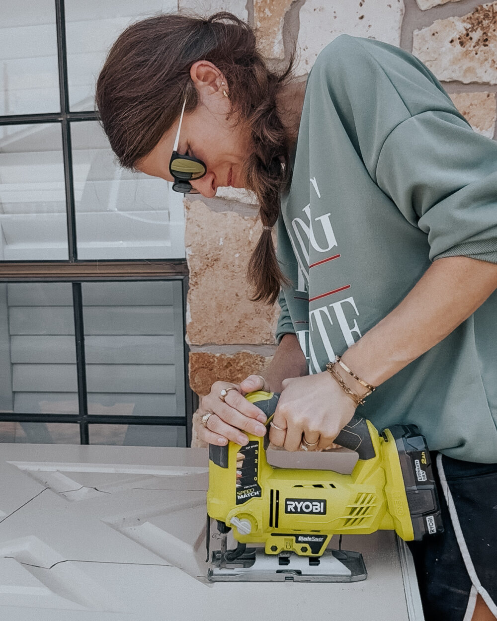 woman cutting out a hole for a doggy door using a jigsaw