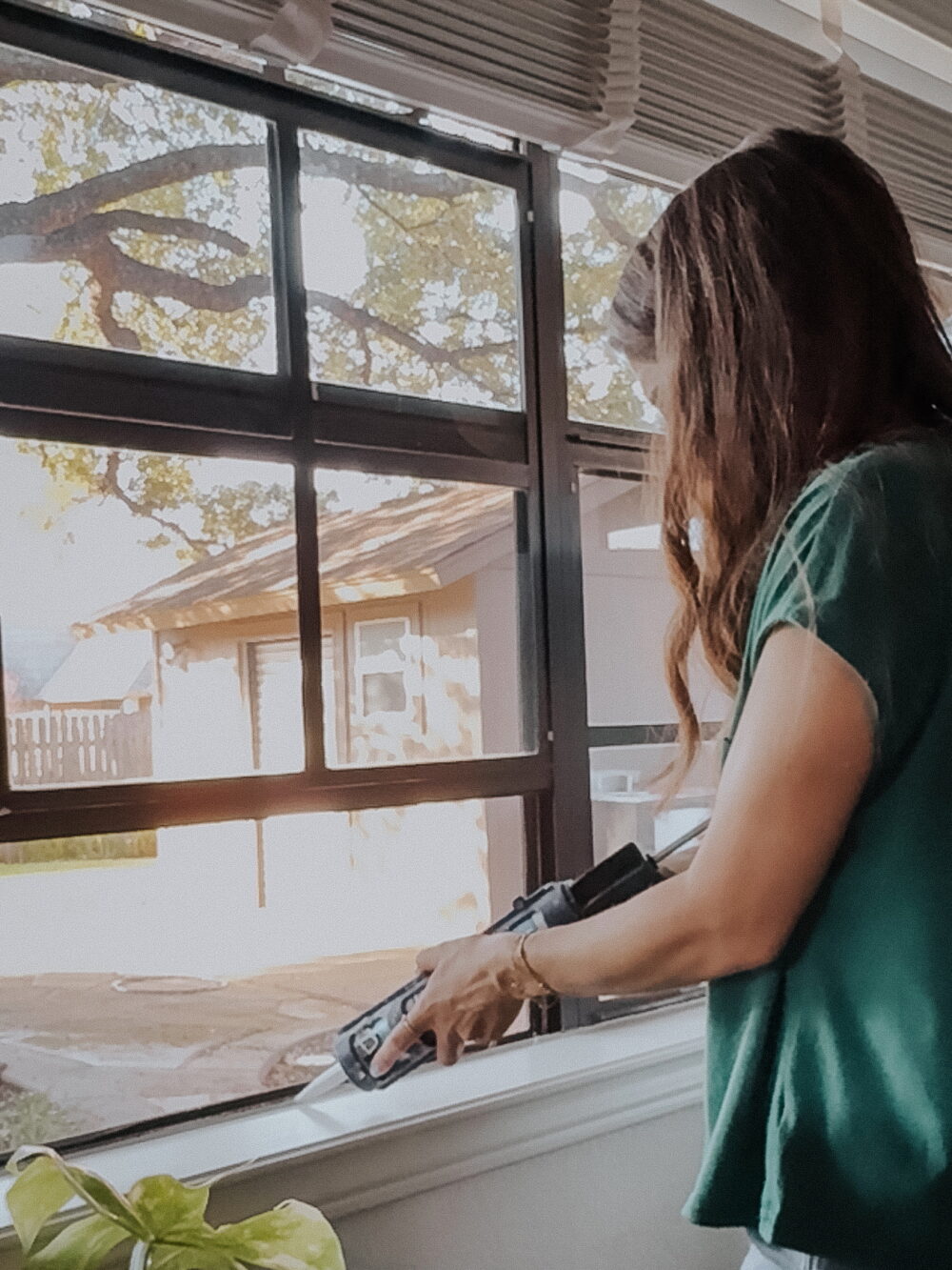 woman caulking around a window