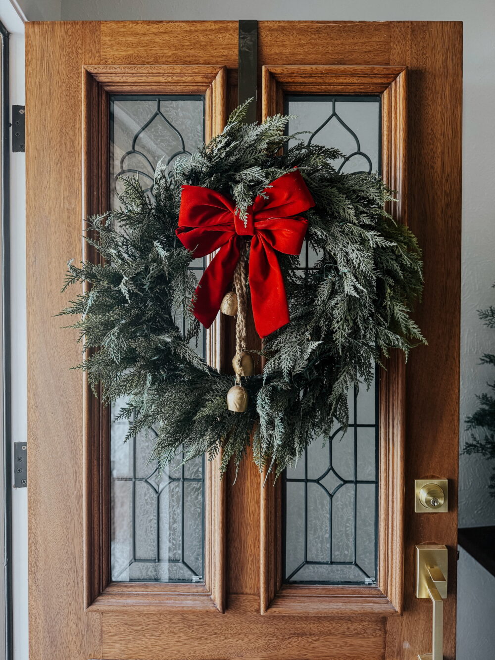 front door with large wreath with a bow and bells on it 
