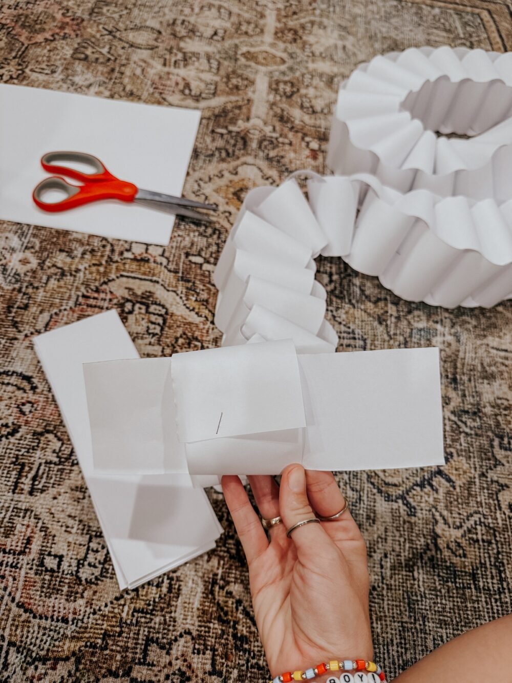 Woman's hand demonstrating how to make a DIY paper chain garland 