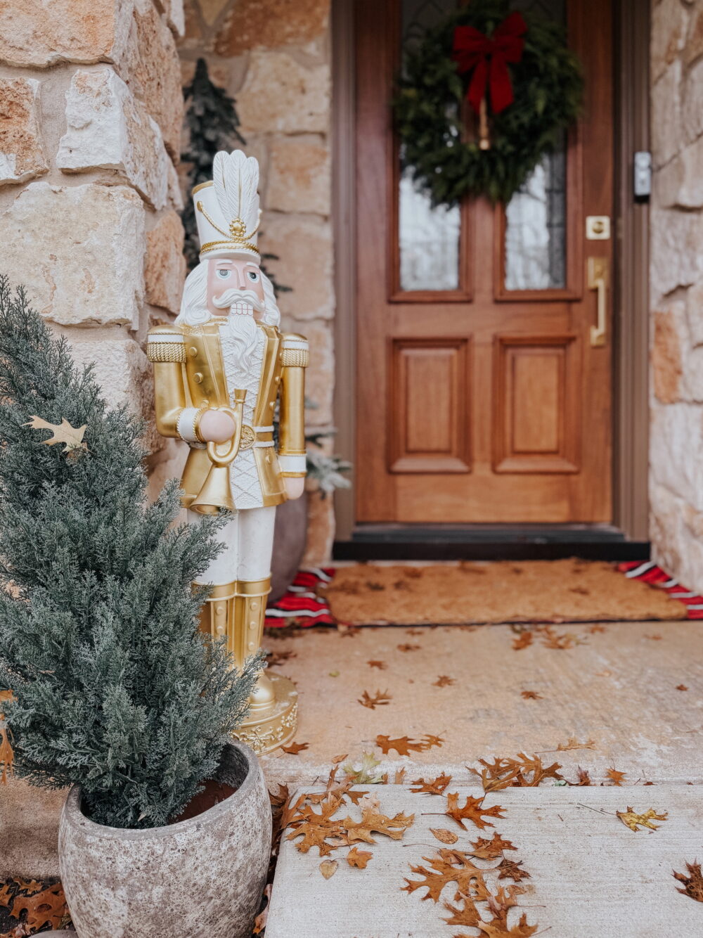 front porch with tall nutcracker and faux trees 