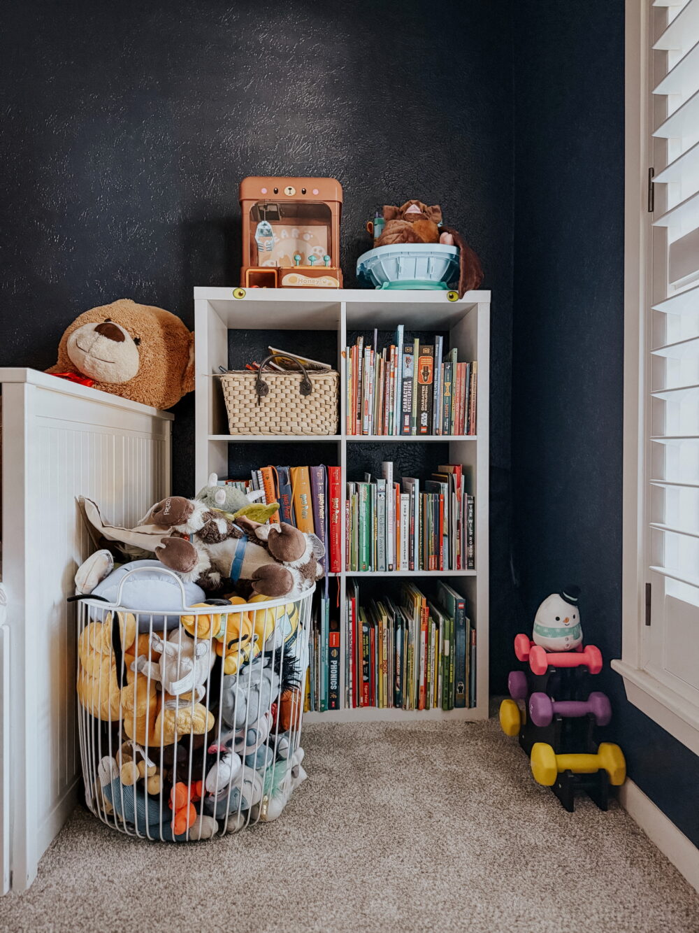 corner of a child's room with a bookcase and a basket of stuffed animals