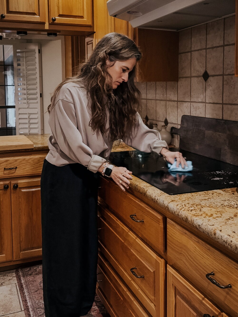 woman cleaning a glass top stove